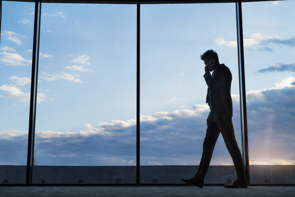 Imagem de um homem com roupa de negócios, andando e falando ao celular